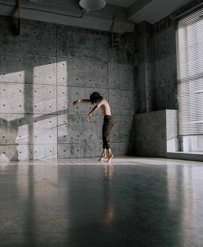 Person practicing gentle movements in a bright minimalist space